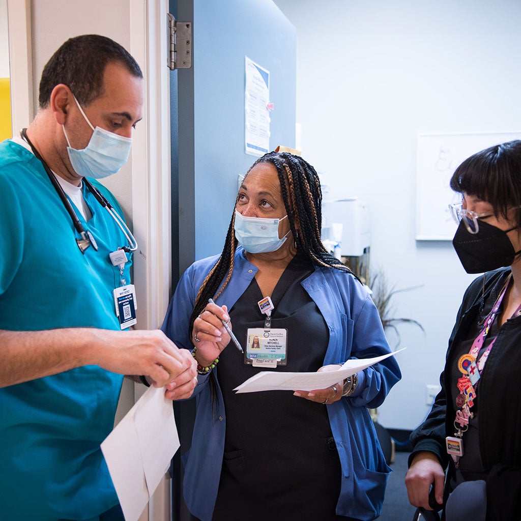 Three health care workers haveing a conversation in clinic hallway.