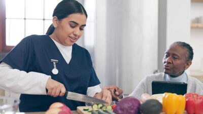 Home health aid helps client in the kitchen