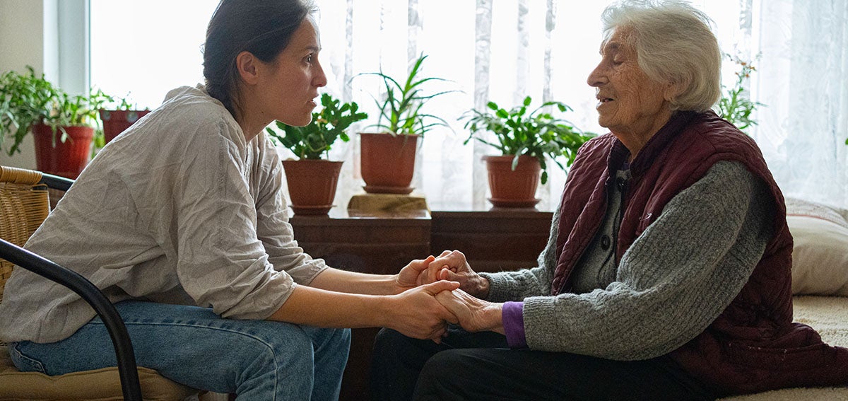 Younger woman assists older woman at home