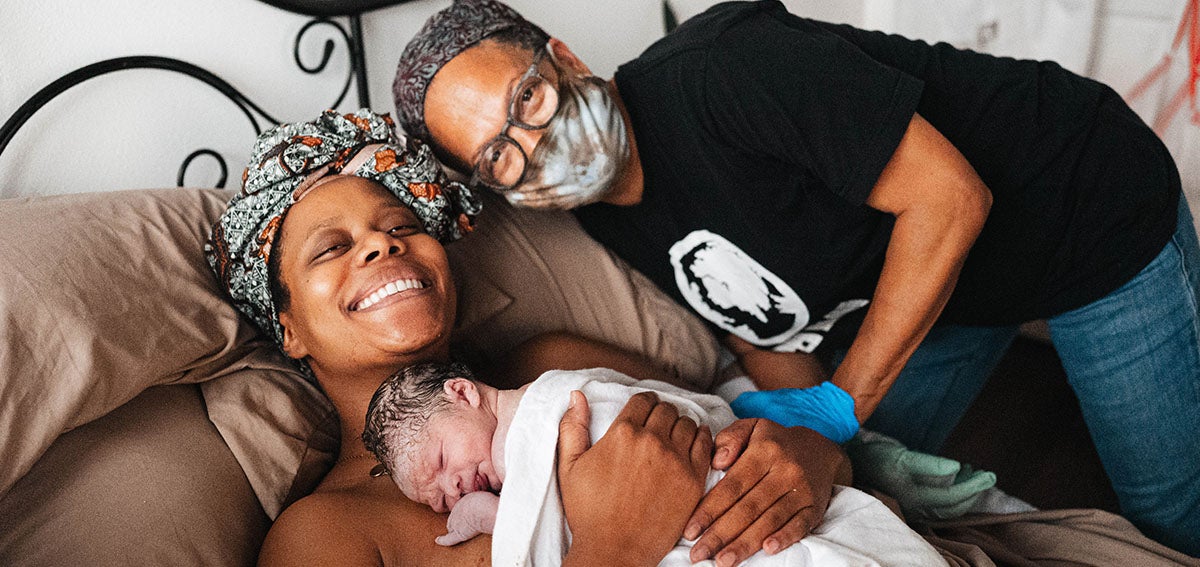 Midwife Kimberly Durdin smiling with second time mom after the birth of her baby at Kindred Space LA Birth Center in South Los Angeles.