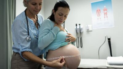 Midwife measures patient during an office visit.