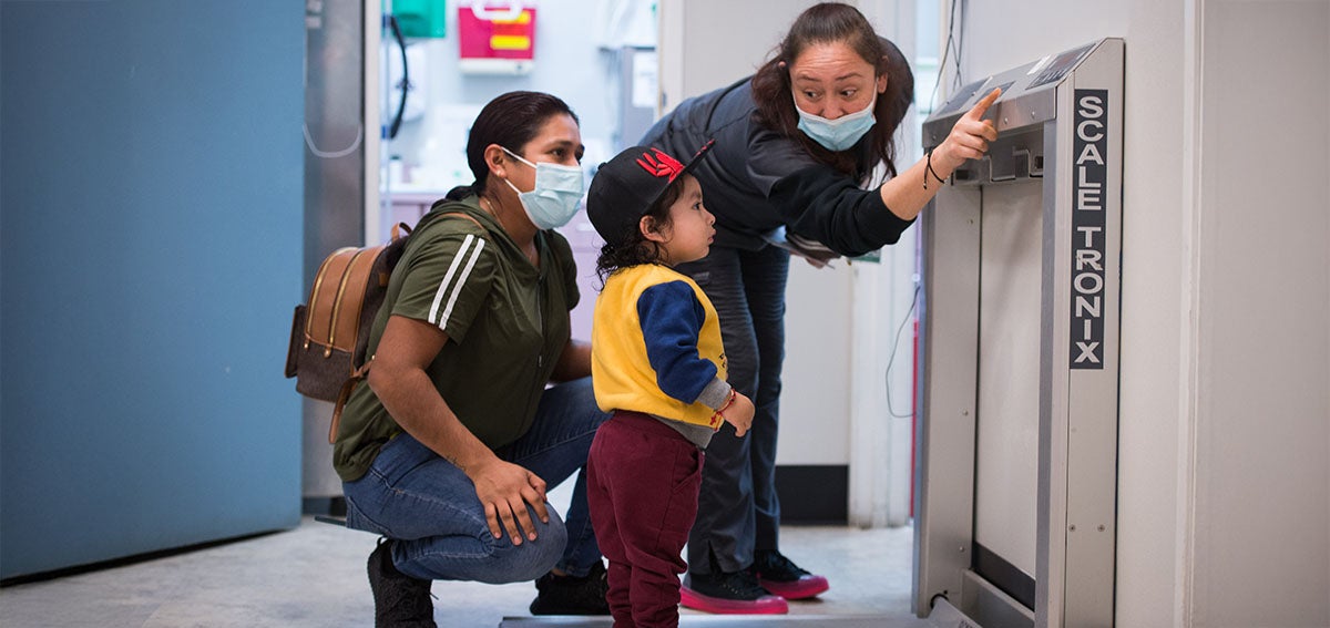 Medical practitioner shows child hoe a scale wotks while his mother watches.