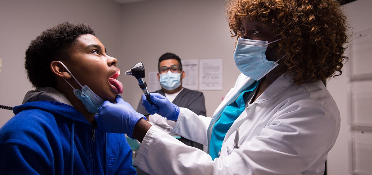 Doctor examines young patients throat.